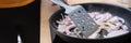 Woman fries onions in skillet in kitchen closeup