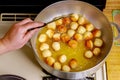 Woman fries munchkins or small donuts in hot oil