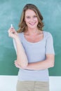 Woman in front of a blackboard holding a piece of chalk