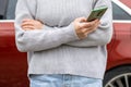 woman in front of lateral door red car in warm pullover blue jeans