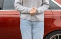 woman in front of lateral door red car in warm pullover blue jeans