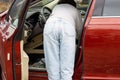 woman in front of lateral door red car in warm pullover blue jeans