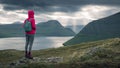 Woman in front of lightbeams through clouds in sky on Faroe Islands Royalty Free Stock Photo