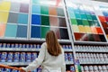 Woman in front of samples of facade and interior paint color palette on wall in hardware store