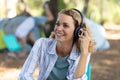 Woman in front tent camping in forest listening music Royalty Free Stock Photo