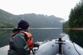 A woman at the front of a zodiac on a tour exploring the ocean, coastlines, forest and islands of Gwaii Haanas, Haida Gwaii