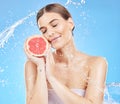 Woman, fruit and smile for skincare hydration, cosmetics or healthy nutrition against a blue studio background. Female