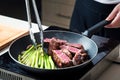 Woman frying beef steak with baby asparagus on the pan Royalty Free Stock Photo