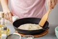 Woman frying mexican flatbread on cast iron pan.