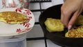 A woman is frying pancakes. Shifts the finished pancakes from the pan to the plate