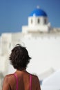 Woman with fuchsia dress looks at a dome of a church in Oia, Santorini