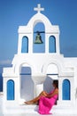 Woman with fuchsia dress sits in the bell tower of a small church in Oia in Santorini Royalty Free Stock Photo