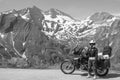 Woman in full biker outfit, Black and white. Touring motorcycle with big bags. Copy space. The snowy peaks of the Alpine mountains Royalty Free Stock Photo