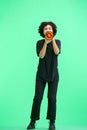 A woman, full-length, on a green background, with a megaphone Royalty Free Stock Photo