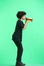 A woman, full-length, on a green background, with a megaphone Royalty Free Stock Photo