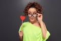 Woman in funny glasses looking at red heart Royalty Free Stock Photo