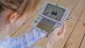 Woman gamer using game console Nintendo 3ds with AR app