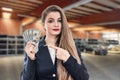 Woman in garage on background of tires showing dollar