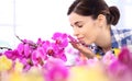 Woman in the garden of flowers, touches and smells orchid