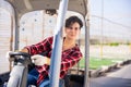 Woman gardener driving agricultural vehicle in hothouse