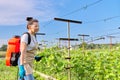 Woman gardener farmer with backpack pressure sprayer sprays vineyard in spring season