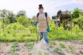 Woman gardener farmer with backpack pressure sprayer sprays vineyard in spring season