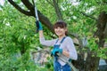 Woman gardener with saw and dry cut branches looking at camera in garden Royalty Free Stock Photo