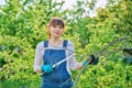 Woman gardener with saw and dry cut branches looking at camera in garden Royalty Free Stock Photo