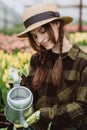 A woman gardener in a hat and gloves waters a flower bed of tulips using a watering can. Gardening hobby concept. Soft selective Royalty Free Stock Photo