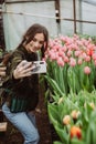 Woman gardener makes selfie. The girl smiles and uses a mobile phone in the tulip flowers greenhouse. Soft selective focus