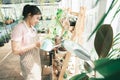 Young woman plant owner shop watering plants in a plant shop. Royalty Free Stock Photo