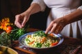 woman garnishing couscous and vegetable salad with herbs
