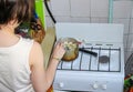 A woman on the gas stove cooking dumplings in a small pot in the old kitchen