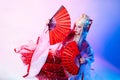 A woman in a geisha costume with fans sits on a white background