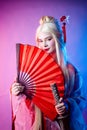 A woman in a geisha costume with a katana and a fan