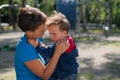 The woman gently hugs her son on the playground. The little boy is naughty and his mother calms him down