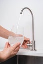 Woman get filtered water from stainless faucet into a glass Royalty Free Stock Photo
