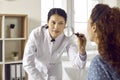 Professional dermatologist using magnifying glass to examine skin on woman's face