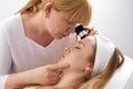 Woman gets professional skin exam at doctor& x27;s office. Dermatologist or cosmetology specialist uses magnifying glass