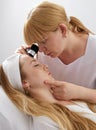 Woman gets professional skin exam at doctor& x27;s office. Dermatologist or cosmetology specialist uses magnifying glass