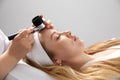 Woman gets professional skin exam at doctor& x27;s office. Dermatologist or cosmetology specialist uses magnifying glass