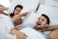 Woman getting disturbed with man snoring on bed