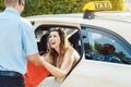 Woman getting out of taxi and the driver helping her