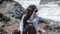 Woman from Ghana sits on rocks in Axim