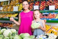 Woman with girl buying cabbage in vegetables section Royalty Free Stock Photo