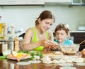 woman with a girl cooking red fish dumplings together at home kitchen Royalty Free Stock Photo