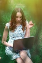 Woman or girl in a dress, with a laptop and headphones, sits on Royalty Free Stock Photo