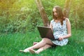 Woman or girl in a dress, with a laptop and headphones, sits on Royalty Free Stock Photo