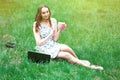 Woman or girl in a dress, with a laptop and headphones, sits on Royalty Free Stock Photo