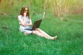 Woman or girl in a dress, with a laptop and headphones, sits on Royalty Free Stock Photo